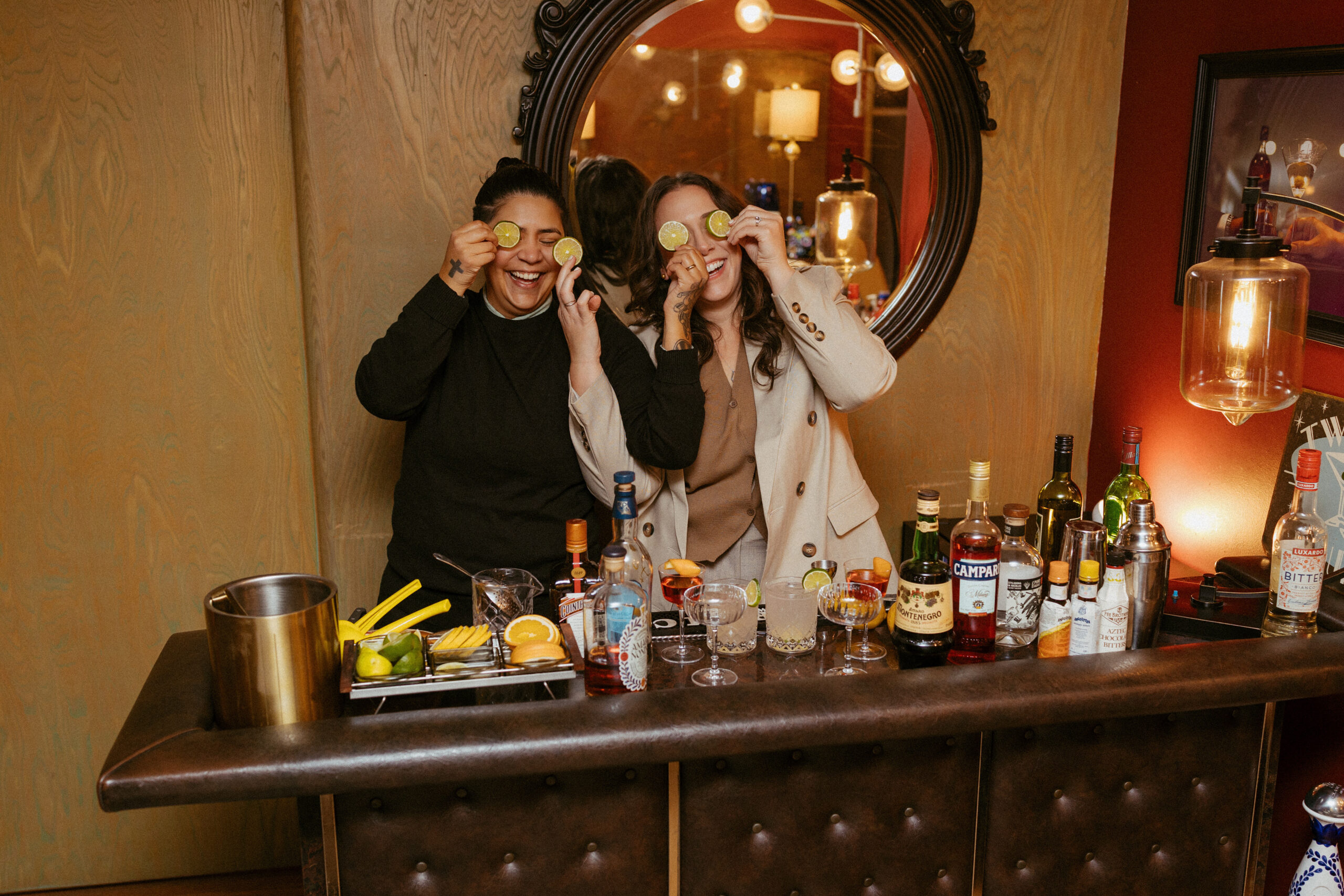 Quinn and Lyza laughing while making cocktails during their indoor engagement session